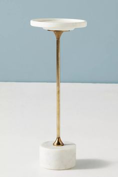 a white table with a gold plate on it and a blue wall in the background