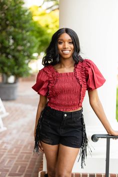 Perfectly girly in this Tandy Top. Cropped and cute. Tandy features shoulder ruffle and puff sleeve, smocked bodice that provides great stretch, and a cropped length. We would style her with our John Skort and Boots for gameday! Product Details: Fit: The Tandy Top fits true to size Length: Cropped length. The small measures 12.5" from shoulder to hem Bust: Not fitted- smocking allows for good stretch. Bra friendly. Waist: Relaxed fit Fabric: The fabric doesn't contain stretch Material: 100% Rayo Flirty Puff Sleeve Top For Day Out, Cute Fall Puff Sleeve Tops, Cute Puff Sleeve Tops For Fall, Cute Ruffled Puff Sleeve Tops, Fall Smocked Short Sleeve Top With Ruffles, Fall Cotton Smocked Top With Ruffles, Fall Short Sleeve Smocked Top With Ruffles, Fall Smocked Top With Ruffles And Short Sleeves, Cute Ruffled Smocked Top For Day Out