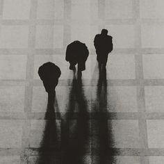 two people standing in the middle of a checkered floor with their shadows on them