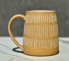 a yellow coffee mug sitting on top of a white countertop next to a gray wall