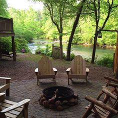 a fire pit surrounded by wooden chairs and trees