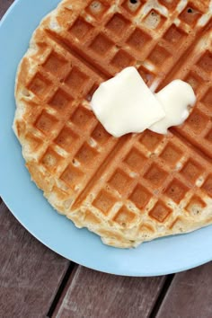 a blue plate topped with waffles covered in butter on top of a wooden table