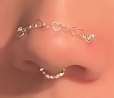 a close up view of a nose piercing with pearls on the side and hearts in the middle