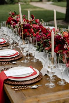 the table is set with red flowers and place settings for an elegant dinner or party