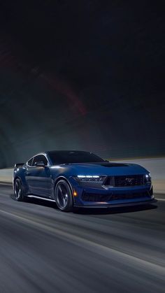 a blue sports car driving down the road at night