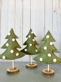 three small green christmas trees sitting on top of a wooden table next to each other