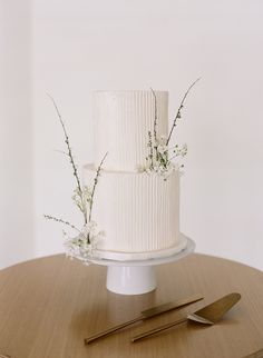 a white wedding cake sitting on top of a table next to a knife and fork