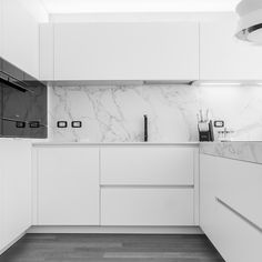 a kitchen with white cabinets and marble counter tops, along with an oven on the wall