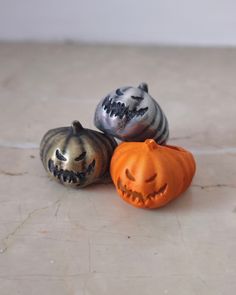 three small pumpkins with faces painted on them