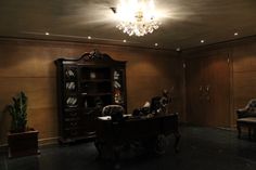 an empty room with a desk, chair and bookcase on the floor in front of a chandelier