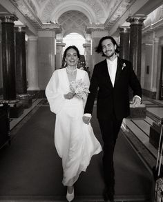 a man and woman walking down a hall holding hands