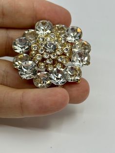 Add some sparkle to any occasion with this vintage Flower Cluster Rhinestone Clear Brooch Pin. The stunning round Rhinestone gems are set in an elegant cluster shape, making it the perfect accessory for weddings, anniversaries, birthdays, and more. The pin's intricate flower design adds a touch of charm, making it a great gift for Mother's Day, Christmas, graduation, or Valentine's Day. This Brooch Pin is a one-of-a-kind piece, handcrafted with care and attention to detail. Its vintage style adds a touch of nostalgia, making it a timeless addition to any jewelry collection. Whether you're dressing up or adding some flair to your everyday look, this stunning piece is sure to turn heads. Flower Cluster Silver Rhinestone Clear Brooch Pin Vintage Materials: silver tone metal & rhinestones Cond Glamorous Crystal Brooches As Gift, Glamorous Crystal Brooches For Gifts, Glamorous Crystal Brooch As Gift, Crystal Brooches With Rhinestones For Anniversary, Wedding Crystal Brooches With Sparkling Stones, Gold Brooches With Rhinestones For Anniversary, Gold Crystal Brooches With Bling, Gold Crystal Brooches For Party, Elegant Round Rhinestone Brooches