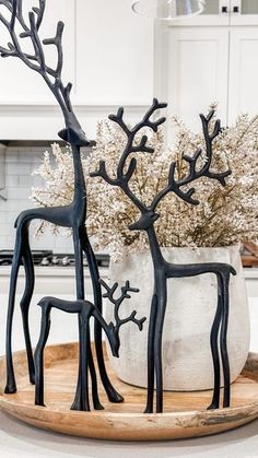 two metal deer sculptures sitting on top of a wooden tray