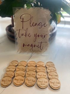 a table topped with lots of wooden magnets next to a sign that says please take your magnet