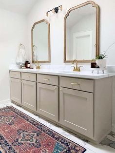 a bathroom with two sinks, mirrors and rug on the floor in front of it