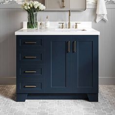 a bathroom vanity with blue cabinets and white flowers on the counter top, in front of a mirror