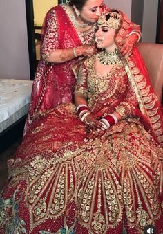 two women dressed in red and gold are posing for a photo together on their wedding day