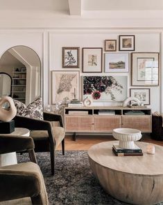 a living room filled with furniture and framed pictures on the wall above an oval coffee table