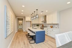 a kitchen with white cabinets and blue island