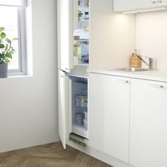 an open refrigerator in the corner of a kitchen next to a window with plants on it