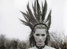 a woman wearing a headdress with feathers on it's head is posing for the camera