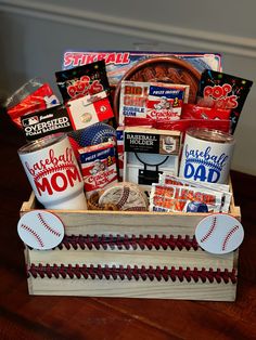 a baseball themed gift box filled with snacks and sports related items on a wooden table