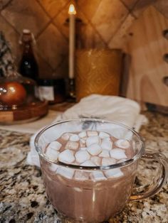 hot chocolate and marshmallows in a glass mug on a marble counter top