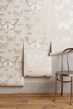 a chair sitting next to a wall with butterflies on it and two sheets in front of the wall