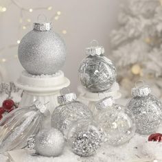 silver and white christmas ornaments in front of a tree