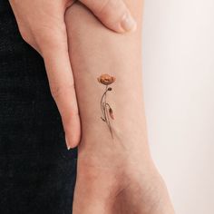 a woman's wrist with a flower tattoo on the left side of her arm