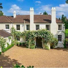 a large white house with ivy growing on it's walls and windows, surrounded by greenery