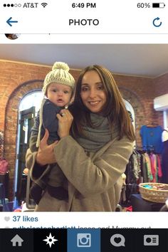 a woman holding a baby in her arms and smiling at the camera while taking a selfie