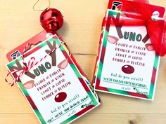 two christmas gift tags on a wooden table with a red ribbon and ornament