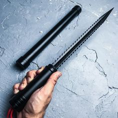 a man holding two black umbrellas on top of a cement floor next to a red hose