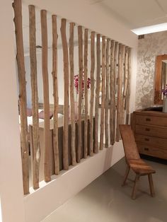 a chair sitting next to a wall made out of wooden sticks and branches with flowers on them