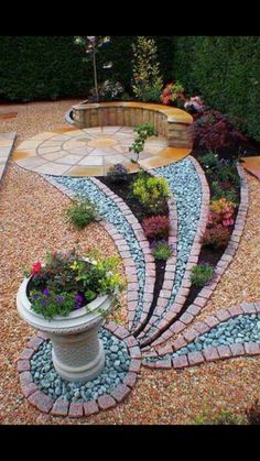 a garden area with gravel, rocks and plants in the shape of a spiral design