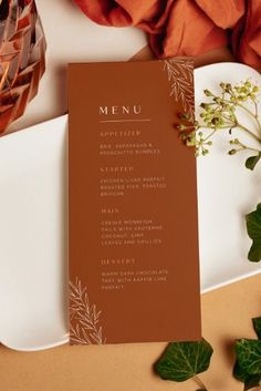 a menu card sitting on top of a white plate next to a vase with flowers