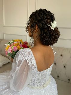 a woman in a wedding dress sitting on a couch with flowers in her hair and holding a bouquet