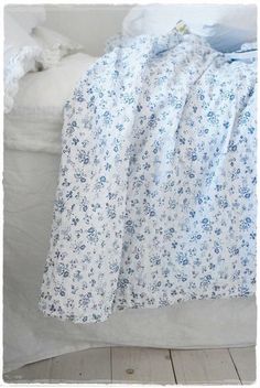 an unmade bed with white sheets and blue flowers