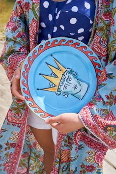 a woman holding a blue plate with a drawing on it