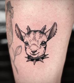 a goat tattoo on the leg of a person's leg with an arrow around its neck