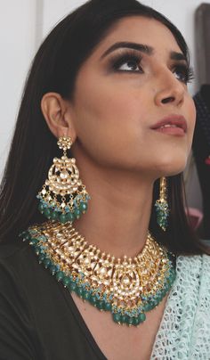 Kundan Gold Plated Indian Bridal Jewellery with Emerald Green stones and light blue agate stones, Semi precious Uncut Kundan Polki Indian Wedding Necklace with Chandbali Earring. Gold Plated kundan and uncut polki set on a silver and copper alloy base. This necklace set is plated with 22k gold and embellished with semi precious emerald green onyx stones and light blue agate stones. Heavy necklace set with chandbaali earrings for bridal dressing.This Sabyasachi inspired necklace with a twist of c Blue Fusion Style Tilla Jewelry, Blue Fusion Tilla Jewelry, Blue Tilla Fusion Jewelry, Blue Kundan Necklaces For Ceremonial Occasions, Ceremonial Blue Kundan Necklaces, Ceremonial Blue Kundan Necklace, Turquoise Fusion Jewelry For Wedding, Blue Chandbali Jewelry With Cutdana Detail, Blue Chandbali Jewelry With Cutdana