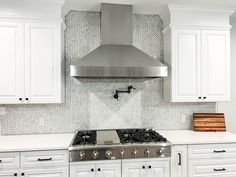 a stove top oven sitting inside of a kitchen next to white cupboards and drawers