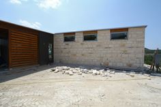 an unfinished house is being built on the side of a hill with large rocks in front of it