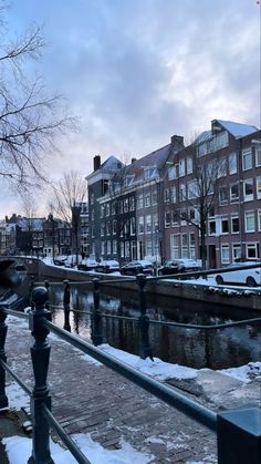 a canal with snow on the ground and buildings in the backgroung area