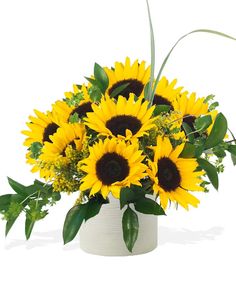 a white vase filled with lots of yellow sunflowers