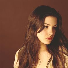 a woman with long brown hair is posing for the camera