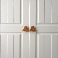 two teddy bears are on the door knobs in front of white doors with wood handles