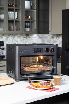 a toaster oven sitting on top of a counter next to a plate of food