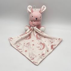 a pink stuffed animal sitting on top of a white blanket with stars and moon designs